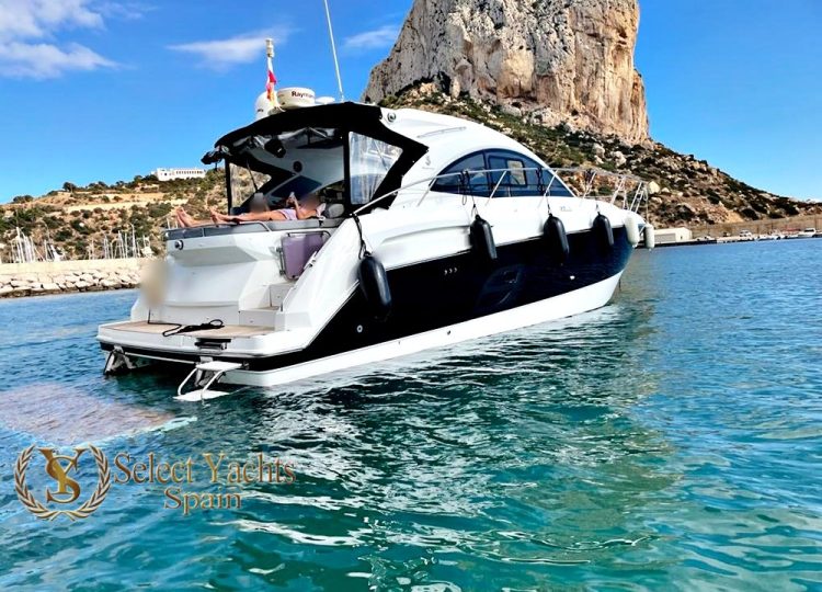 Un yate pequeño a motor en el agua frente a la costa de Altea